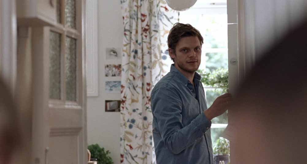 A still from Oslo, August 31st showcasing Thomas's apartment, which is light in colour and has white, floral curtains.