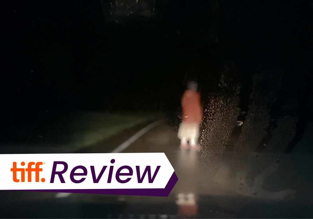 A still from DASHCAM, of a blurry figure in red, seem in the dark through a car's front window. The text on the images reads, 'TIFF Review'.