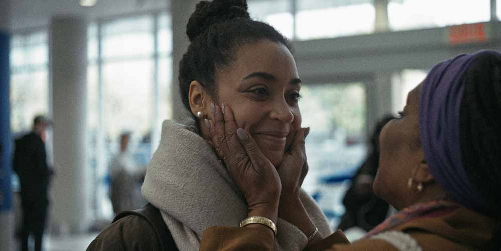 A young woman smiles, her faces cupped by another woman's hands, in Fanmi, one of the best shorts at TIFF 2021.