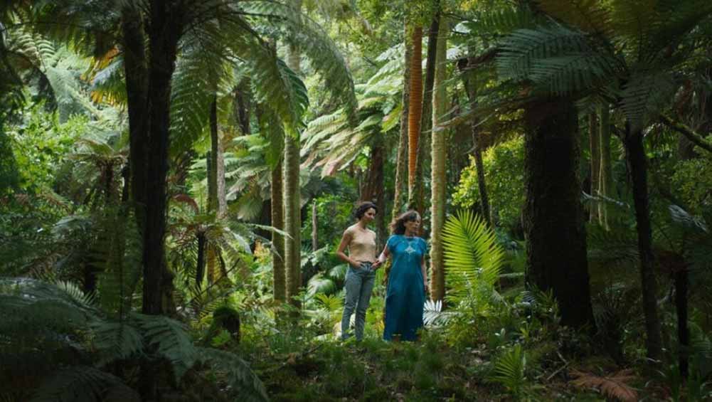 Two small figures stand amidst a sprawling, green jungle landscape in Sycorax, one of the best shorts at TIFF 2021.