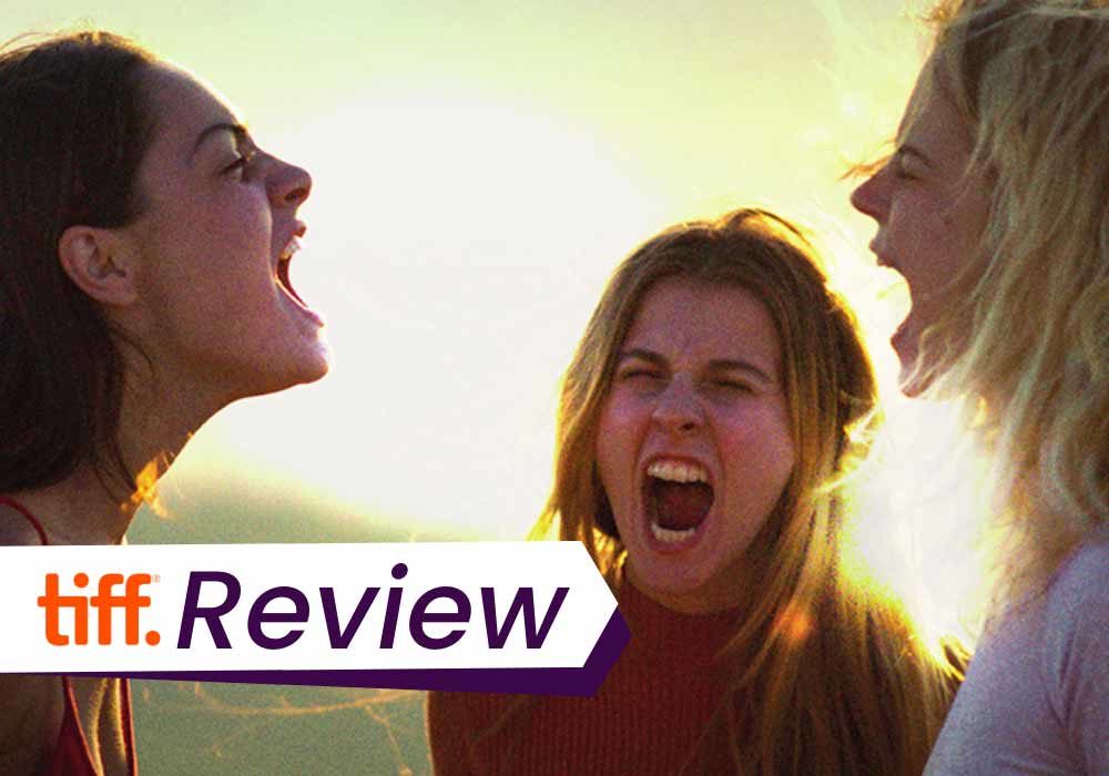 A still from The Hill Where Lionesses Roar, in which the three girls faces each other and scream into the sky. The text on the images reads, 'TIFF Review'.