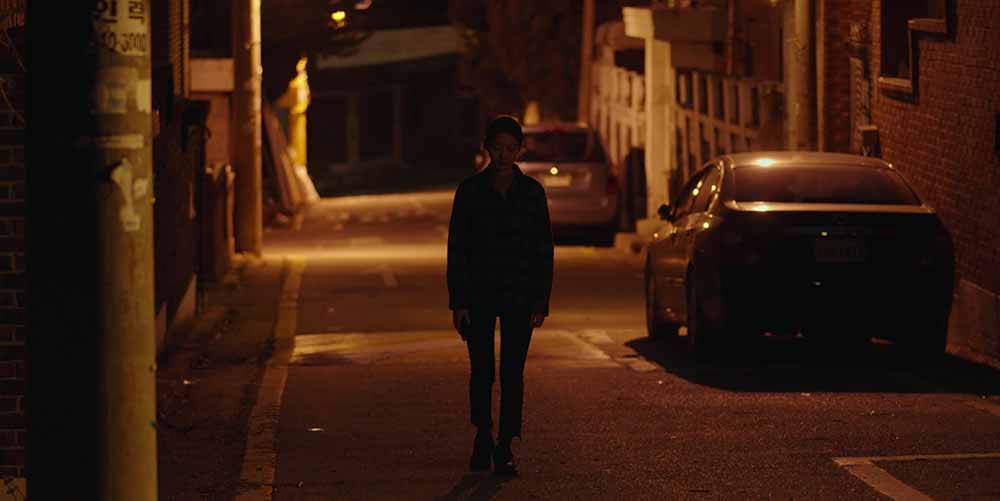 A still from Aloners, in which Jina walks home alone down a dark street.