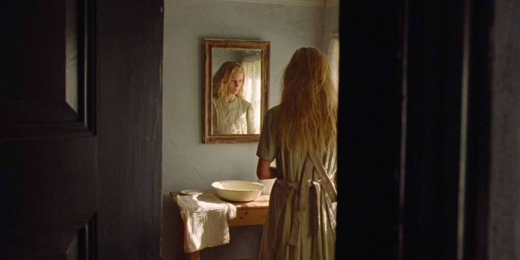 Lise is framed through a door and seen in the mirror in As in Heaven, directed by Tea Lindeburg. Still by cinematographer Marcel Zyskind.
