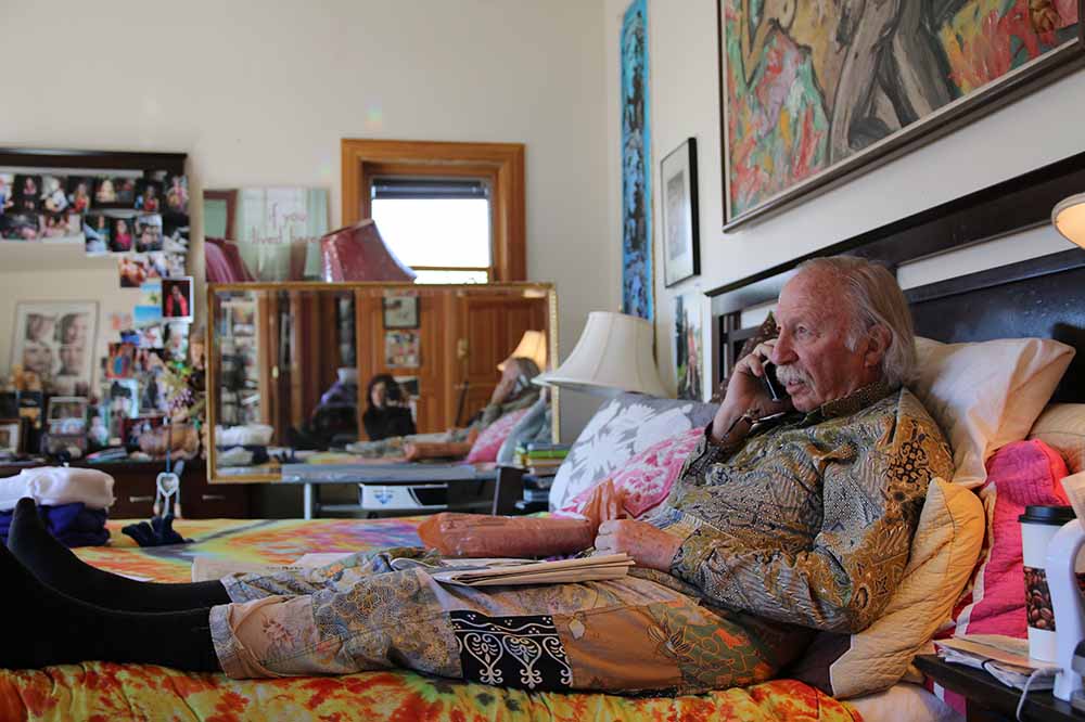 A still from Film About a Father Who by Lynne Sachs, featuring an elderly Ira Sachs Sr. sitting up on a bed and on the phone.