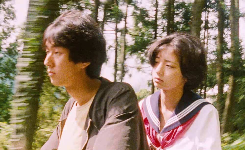 A still from Suzaku, which screens in Japan Society's Flash Forward series. The still features an older boy and his younger female cousin riding a motorbike through the woods.