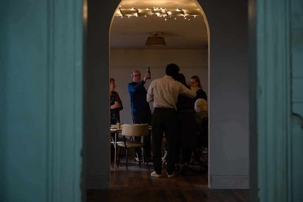 A wide shot from The Humans, in which we see a family gathered in a dining room, seen through a hallway archway.