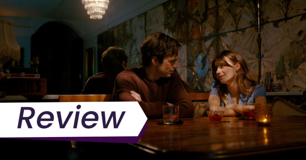 A still from Fresh, in which a young woman and an older man sit together at a damily lit bar. The text on the image reads, 'Review'.