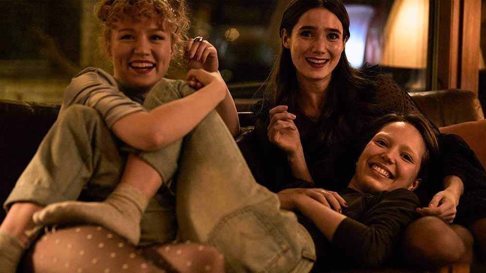 A still from Girl Picture, in which three teenage girls lie sprawled on each other and laughing on a couch.