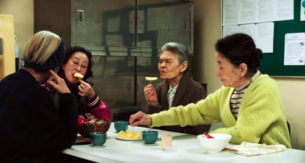Michi shares a meal with her friends near the beginning of Plan 75, directed by Chie Hayakawa. Four elderly women sit around a table eating. 