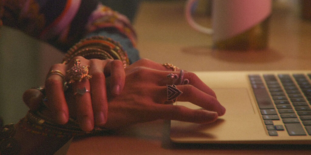 Still of the companion protagonist's hands, touching the trackpad of her laptop, in Sophy Romvari's short It's What Each Person Needs at TIFF 2022. It's What Each Person Needs is on of the top 10 best must-see shorts at TIFF 2022.
