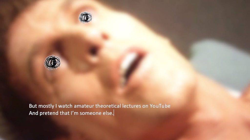 Still from Bigger on the Inside, a short film by Angelo Madsen Minax, featuring the onscreen text that feels typed to the audience. The image is of a YouTube clip of a man's head, who is lying down. There is a black circle drawn on each of his eyes. The onscreen text in white reads "But mostly I watch amateur theoretical lectures on YouTube And pretend that I'm someone else."