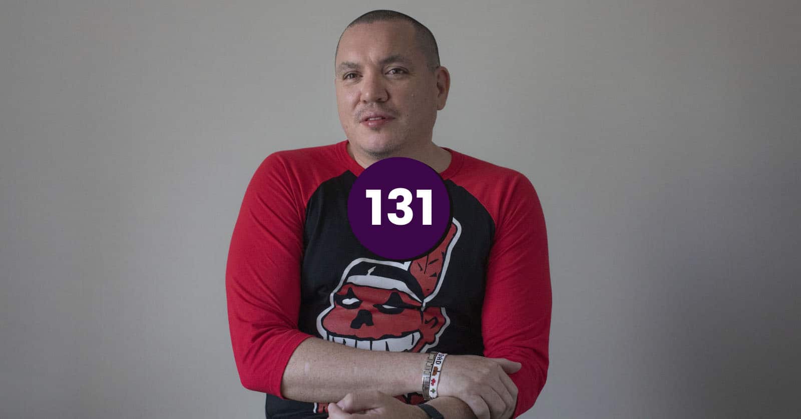 Feature image for the Jeff Barnaby podcast: in memorial. 
Still of Mi'gmaq director Jeff Barnaby, a middle-aged Indigenous man with shaved black hair, in a red and black baseball shirt with a red "Indian" cartoon on it.