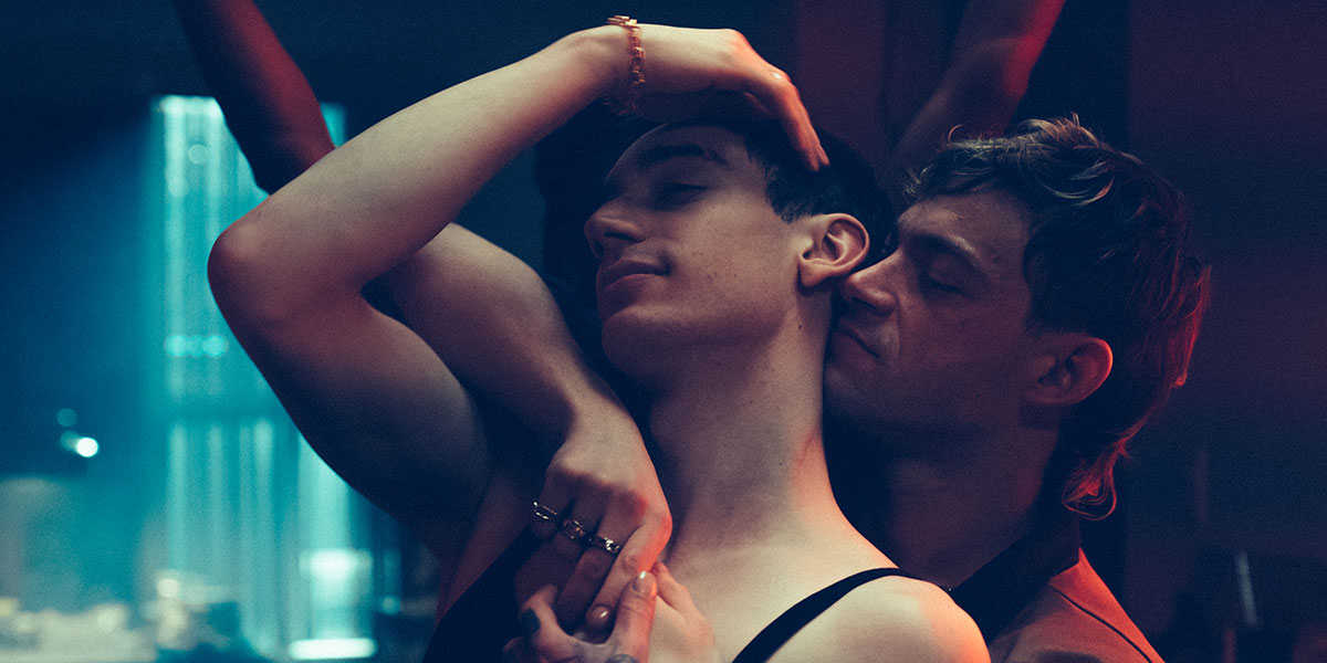 Théodore Pellerin (a lanky white man with dark hair) stars as a drag queen, being embraced by his lover, in Sophie Dupuis' Solo.