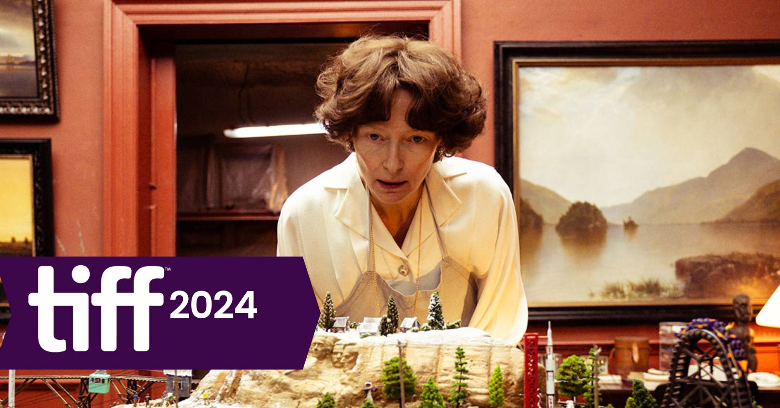 Still of Tilda Swinton standing in front of a miniature town wearing an apron (and a brown bob wig)  in Joshua Oppenheimer's film The End at TIFF 2024, which we discuss on the podcast. Photo courtesy of TIFF.