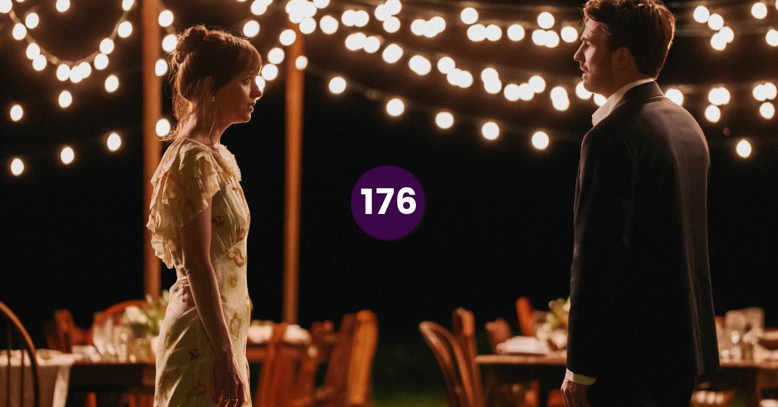 Still of Lucy (Dakota Johnson) and John (Chris Evans) in Materialists (directed by Celine Song), which Alex discusses on the podcast. A white woman in a flowy summer dress and brown hair in a bun faces a white man with dark hair wearing a suit underneath twinkly lights at night.